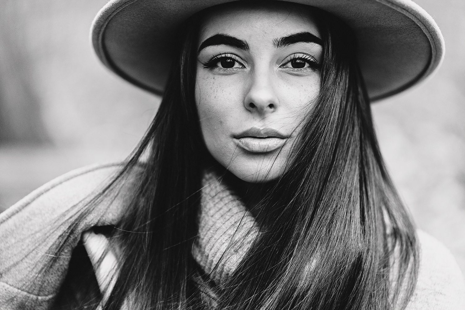 Portrait of woman wearing wide brim hat in black and white.