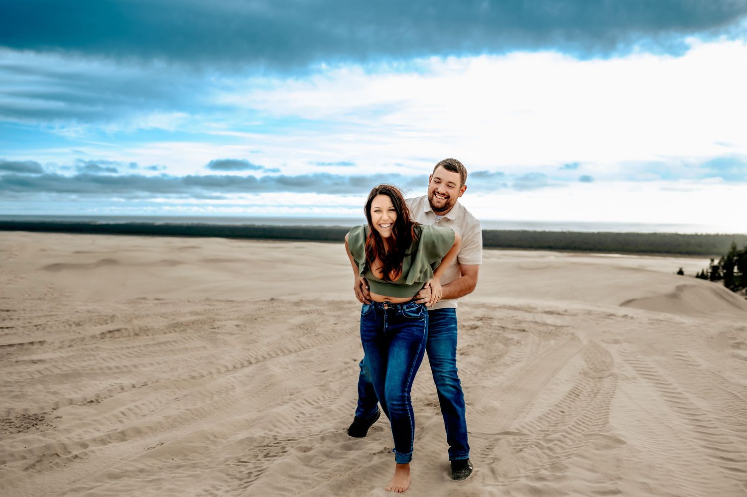 Couple sharing intimate moments on a vast sandy beach landscape.