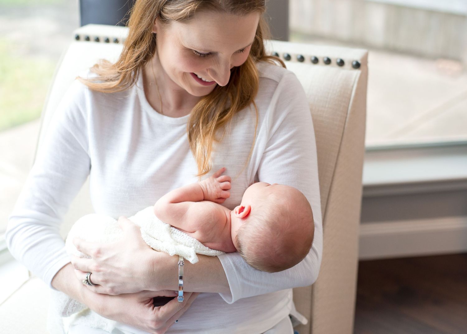 Mother nursing baby in natural window light during intimate lifestyle portrait session.