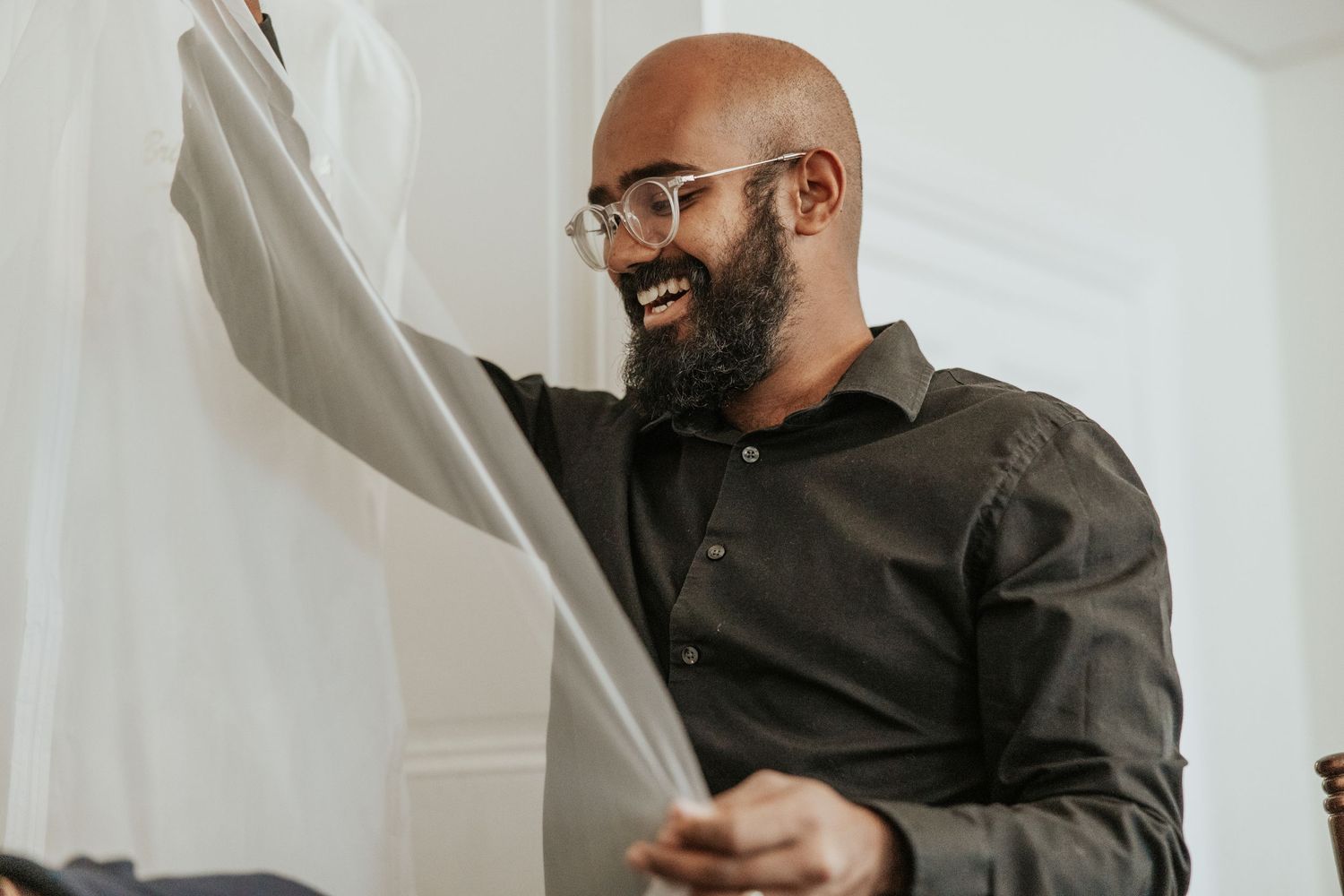 A man in business attire smiles while reading documents.