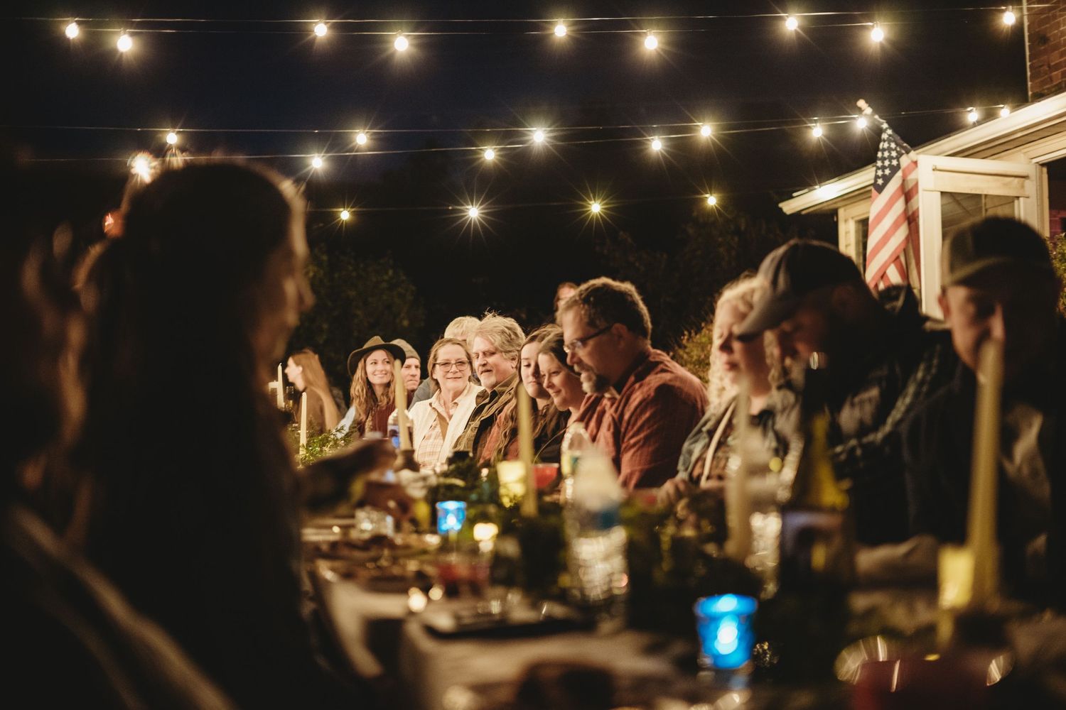 String lights create a warm ambiance at an outdoor evening wedding reception.