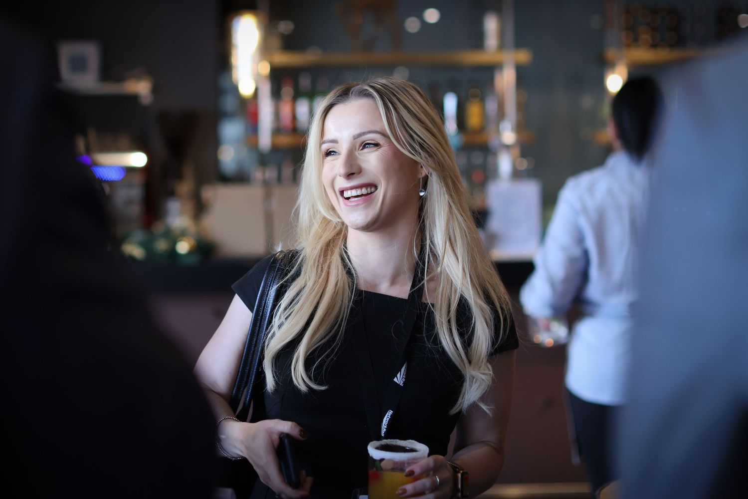 Young woman laughing during casual conversation in dimly lit restaurant setting.
