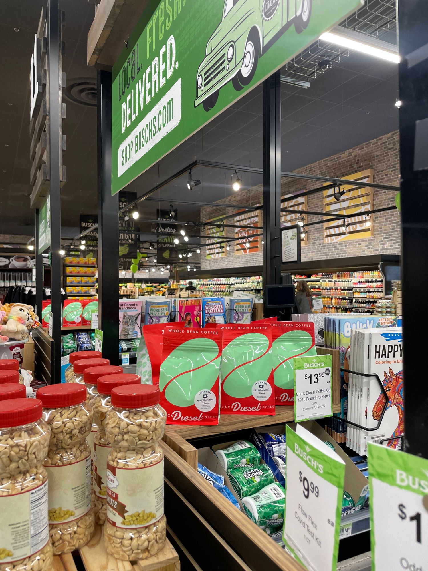 Grocery store shelf displaying various green-packaged health food products and snacks.
