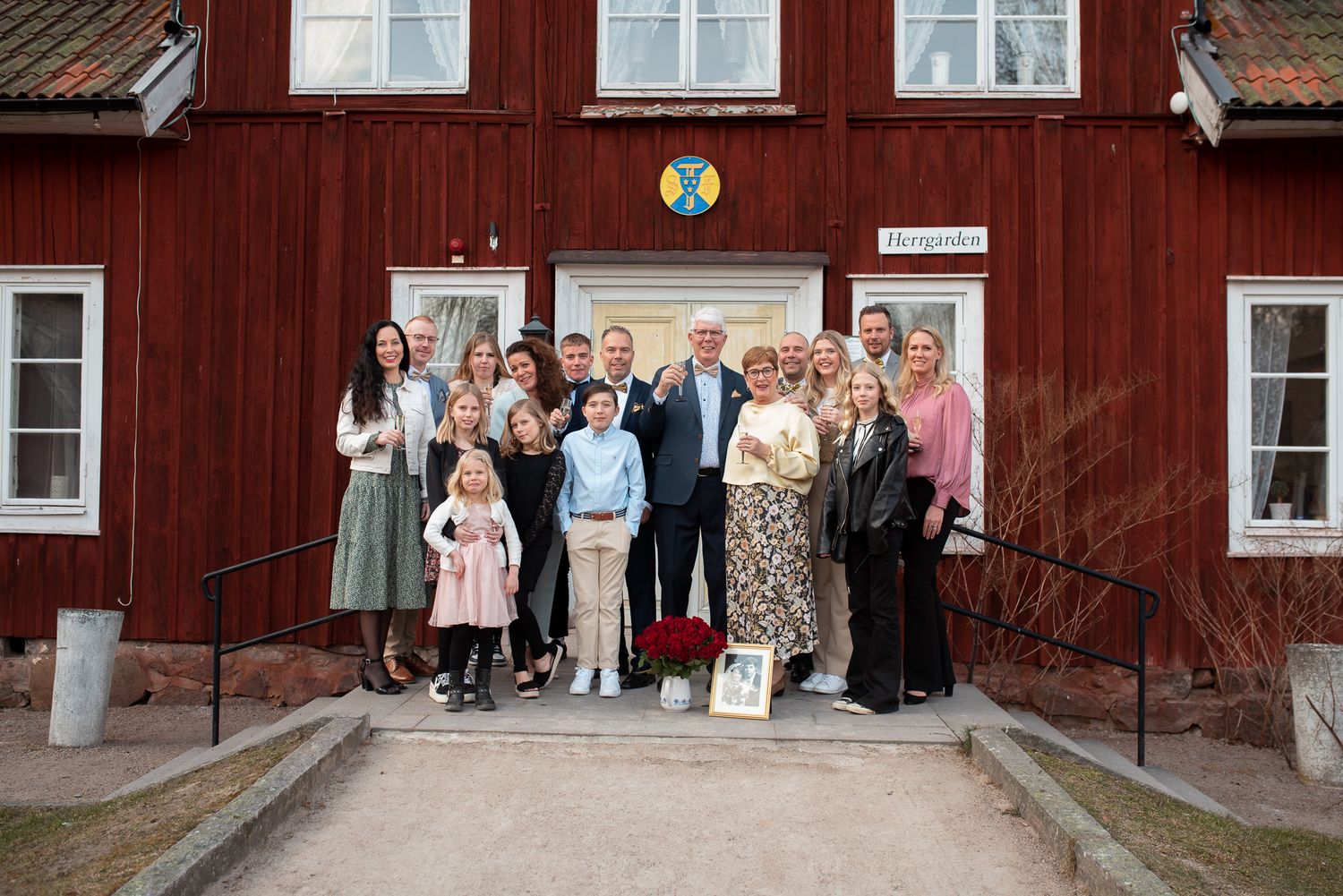 Group photo of wedding guests standing together on steps of red wooden building.