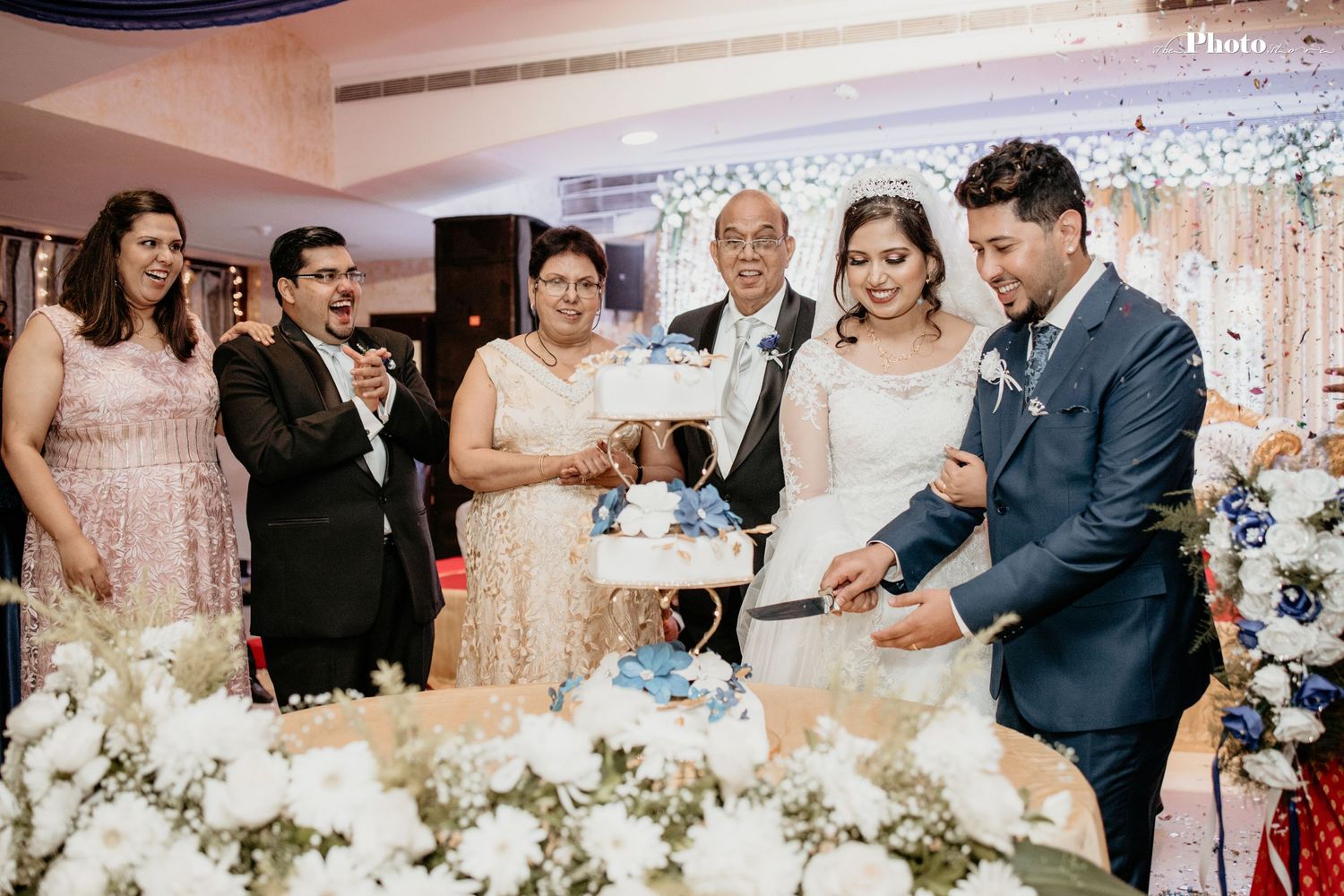 Wedding reception with white floral centerpieces and guests mingling in a decorated venue.