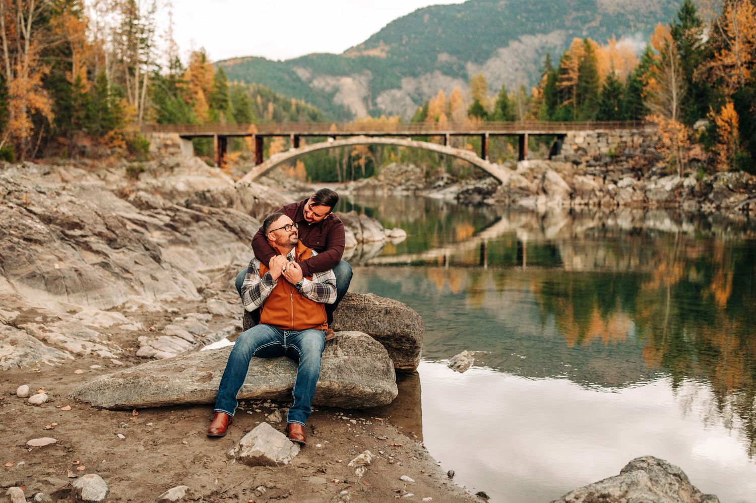 couple sitting on a rock together at Belton bridge in west glacier