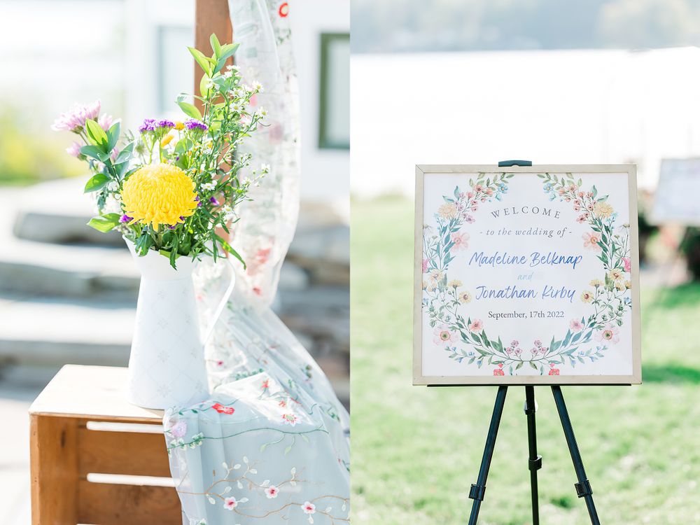 Wedding welcome sign on easel with floral arrangement in white vase against blue sky.