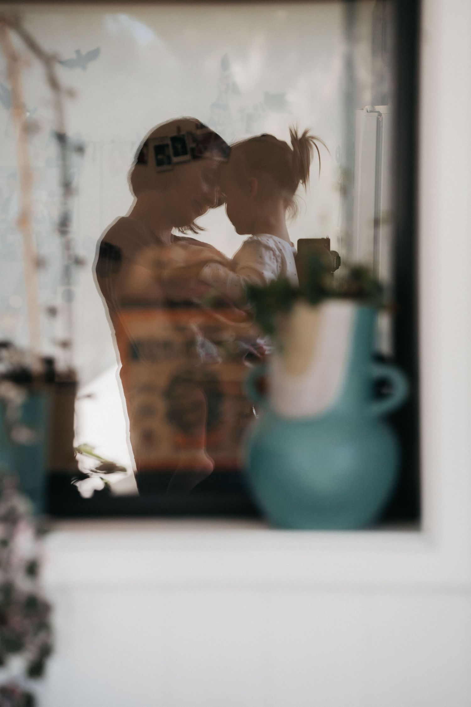 A window reflection of Bethany and a daughter in their home in Perth