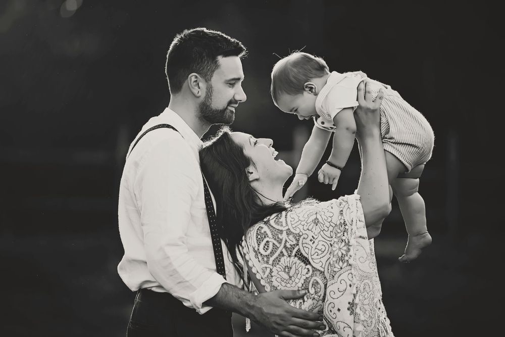 Black and white. John, Anna and their baby Jasper. Mom is holding the baby and they are both looking at him adoringly