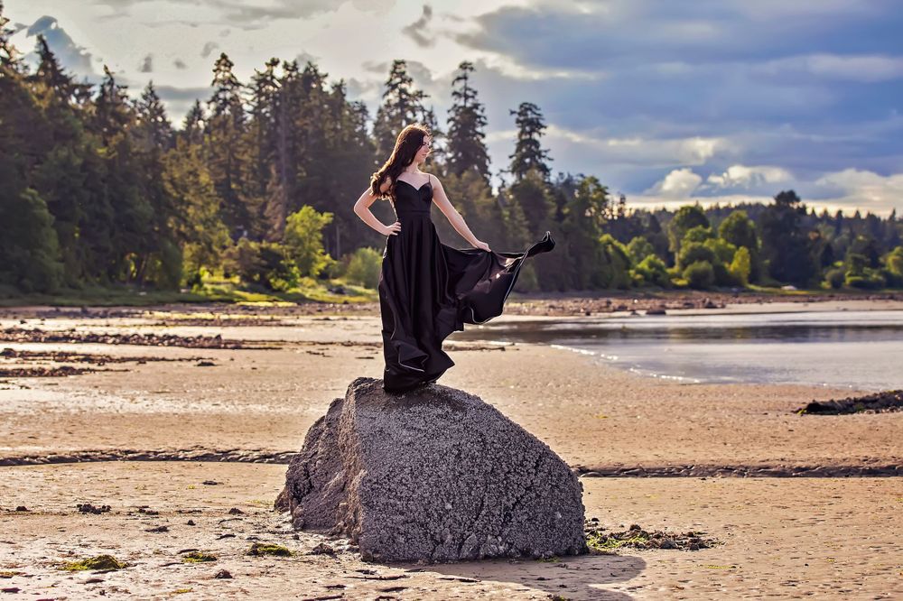 Livea, a striking graduate poses on a rock at Gartley Point in Royston. Wind catching her long, black dress