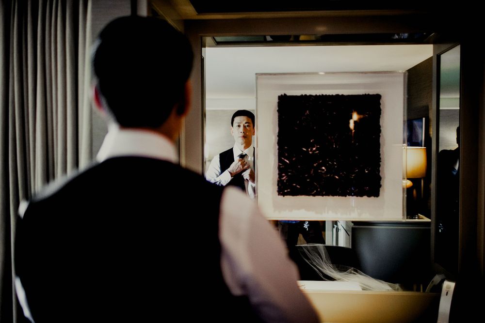 groom adjusting suit in front of mirror