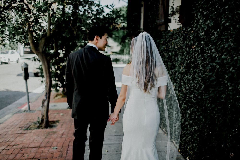 bride and groom holding hands on sidewalk