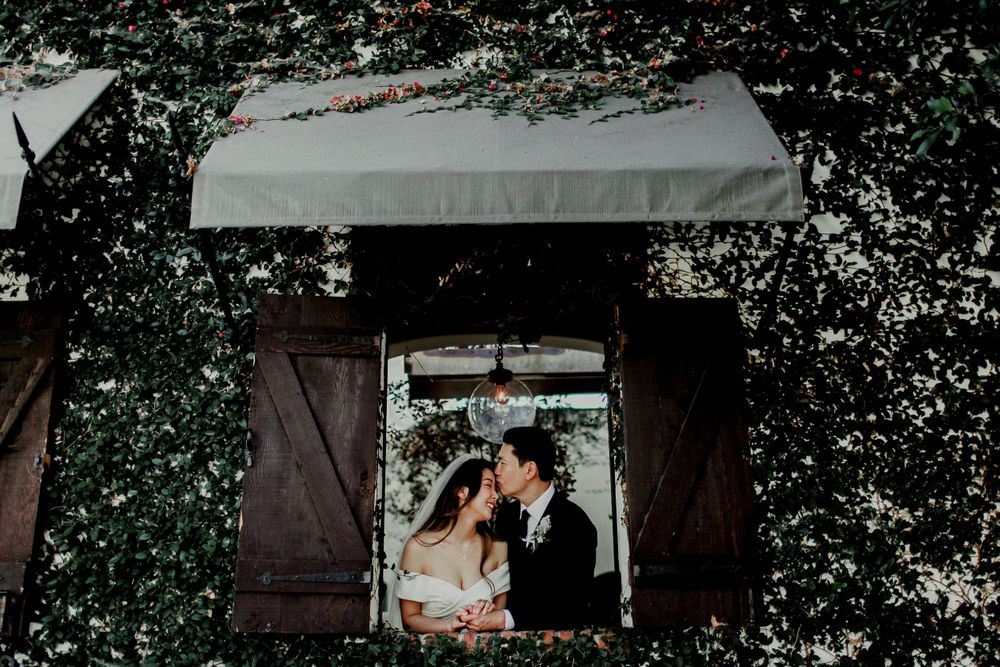 groom kissing bride's head in window