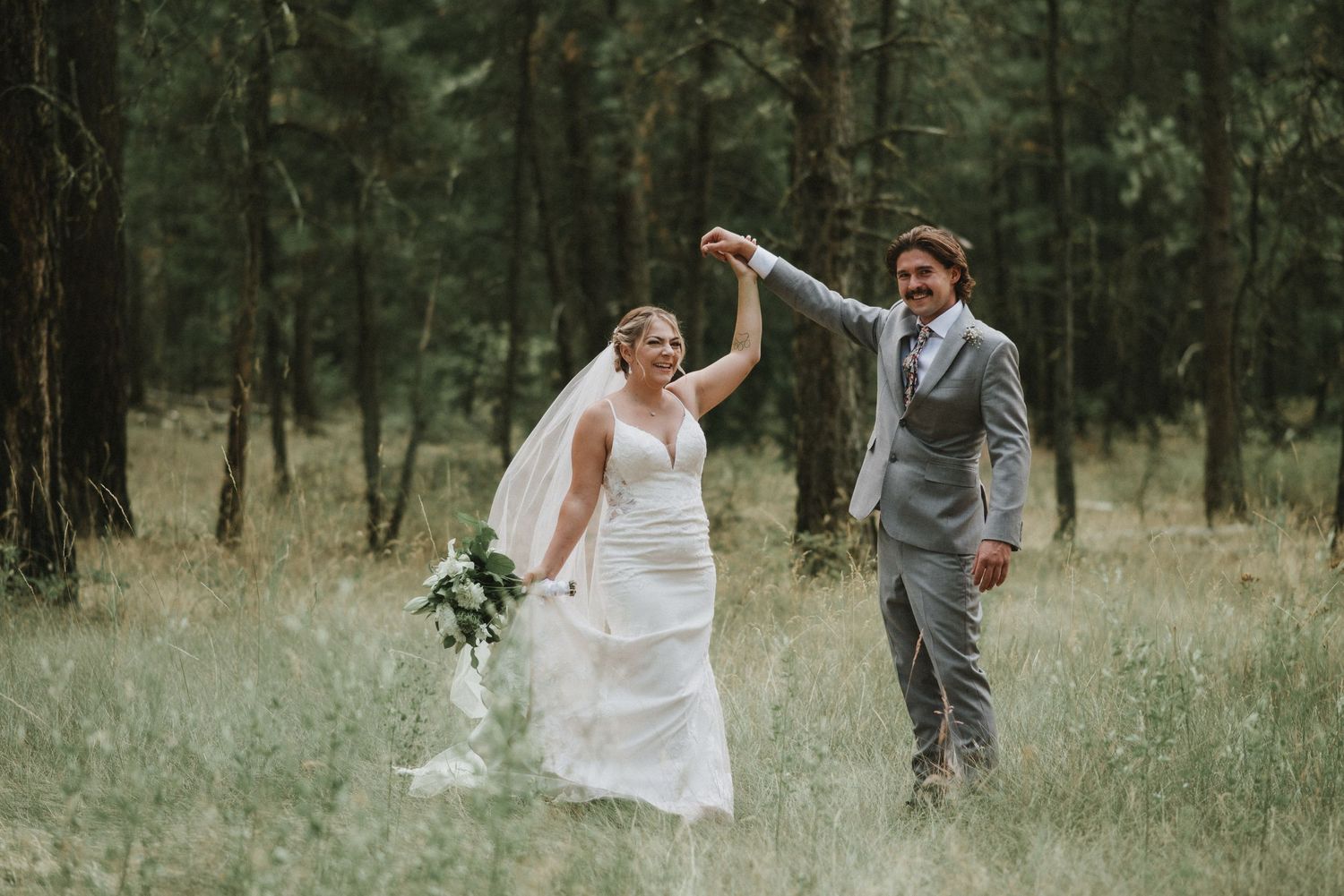 Bride and groom portraits in a grass field. Bride is spinning with the groom.