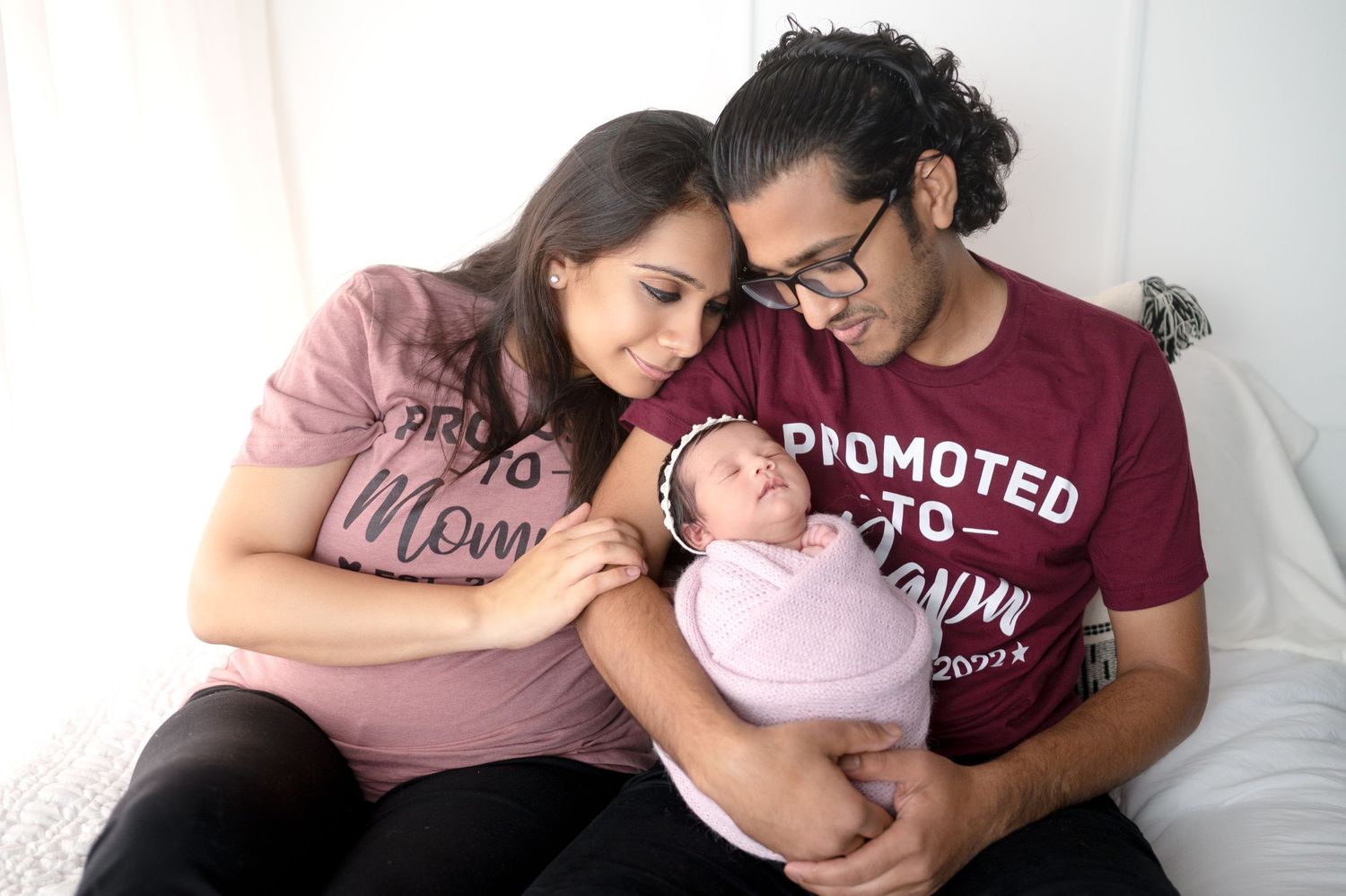 Family photo session showing parents in coordinated outfits cuddling with their newborn.