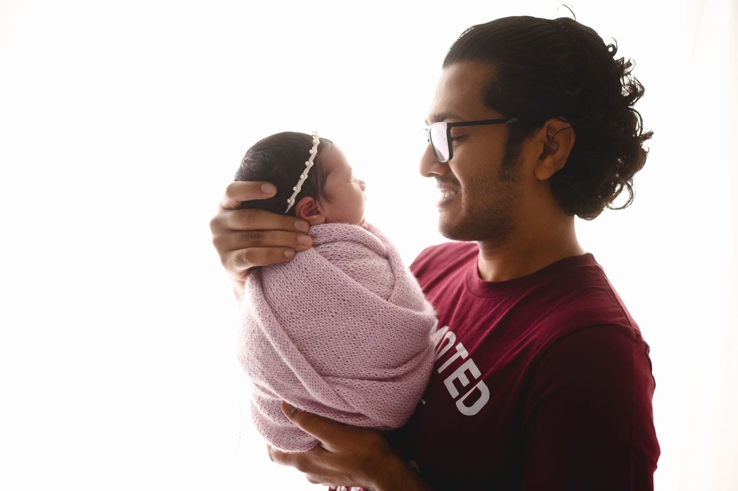 Family photo session capturing tender moments between parents and newborn in coordinating outfits.
