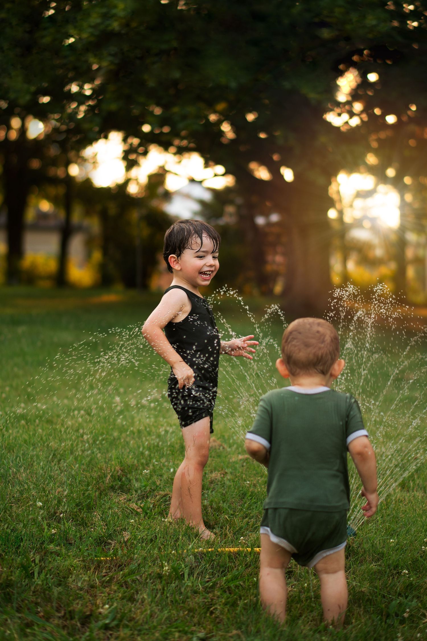 brothers play in sprinkler