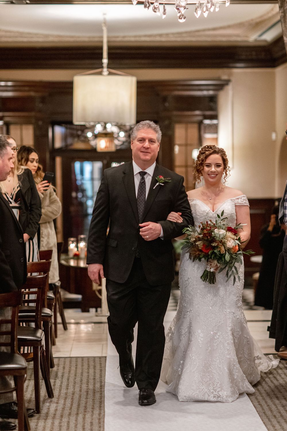 A traditional wedding processional down an elegant carpeted aisle with wooden details.