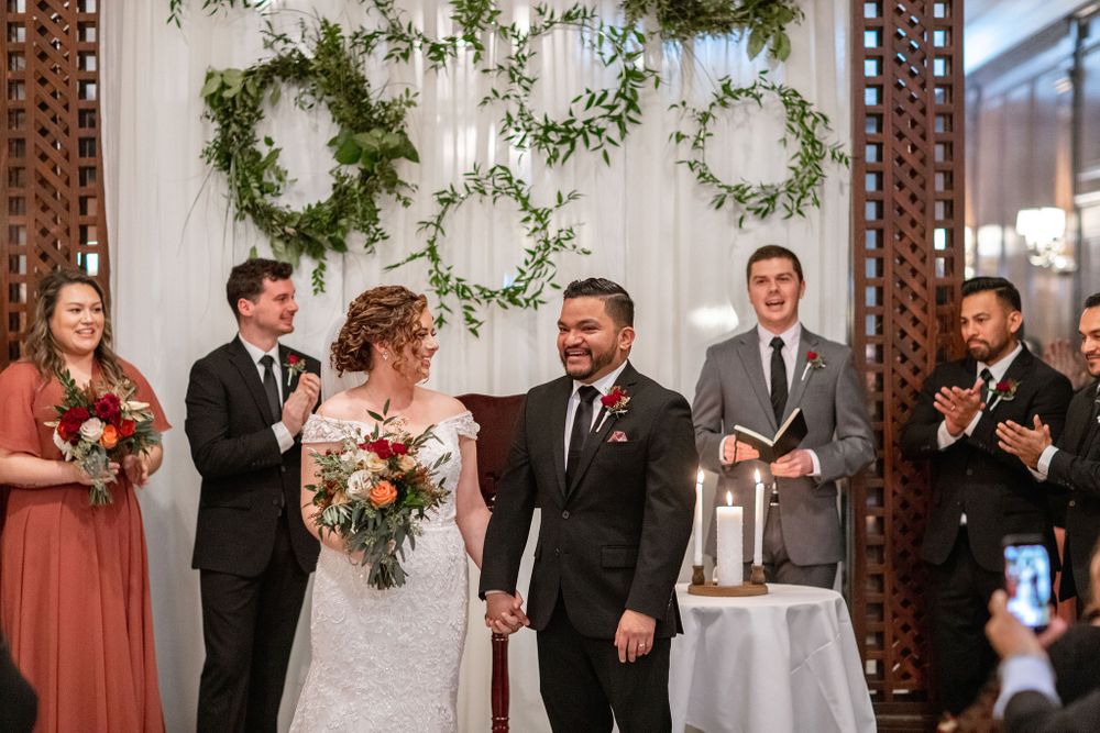 A wedding ceremony with rustic greenery wreaths and burgundy bridesmaids dresses.