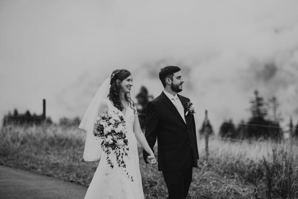 A black and white portrait of newlyweds walking together on a scenic mountain trail.