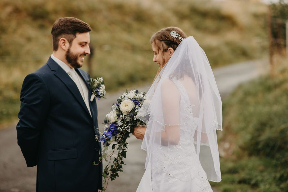 Intimate wedding moment captured with mountain scenery and blue bouquet.
