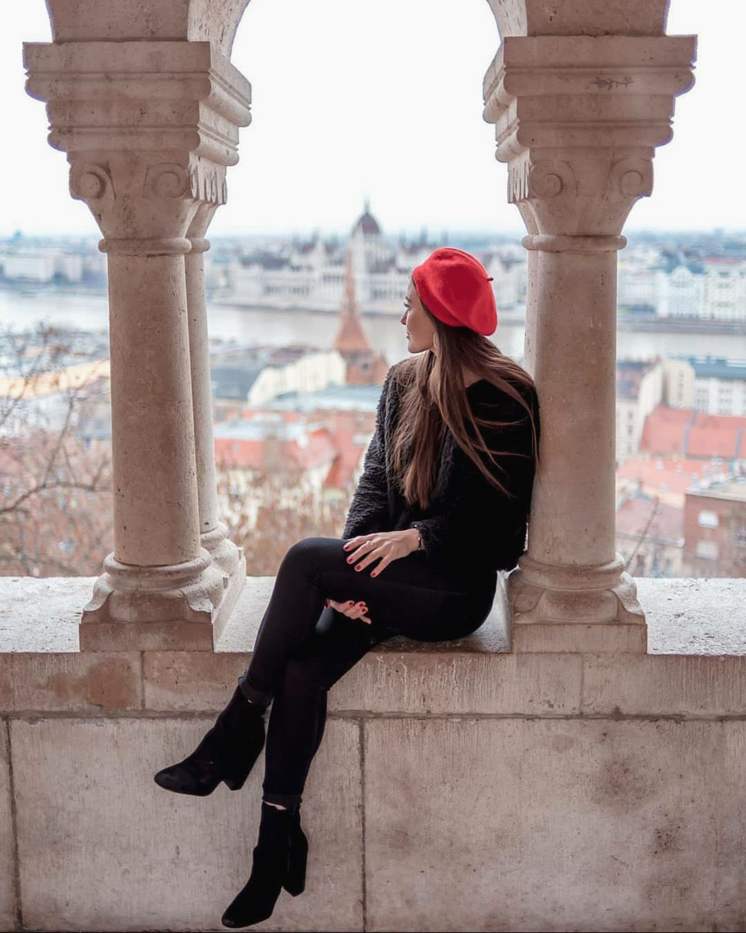 girl sitting with a red hat at fisherman's bastion, posing for her photographer to capture her travel memories