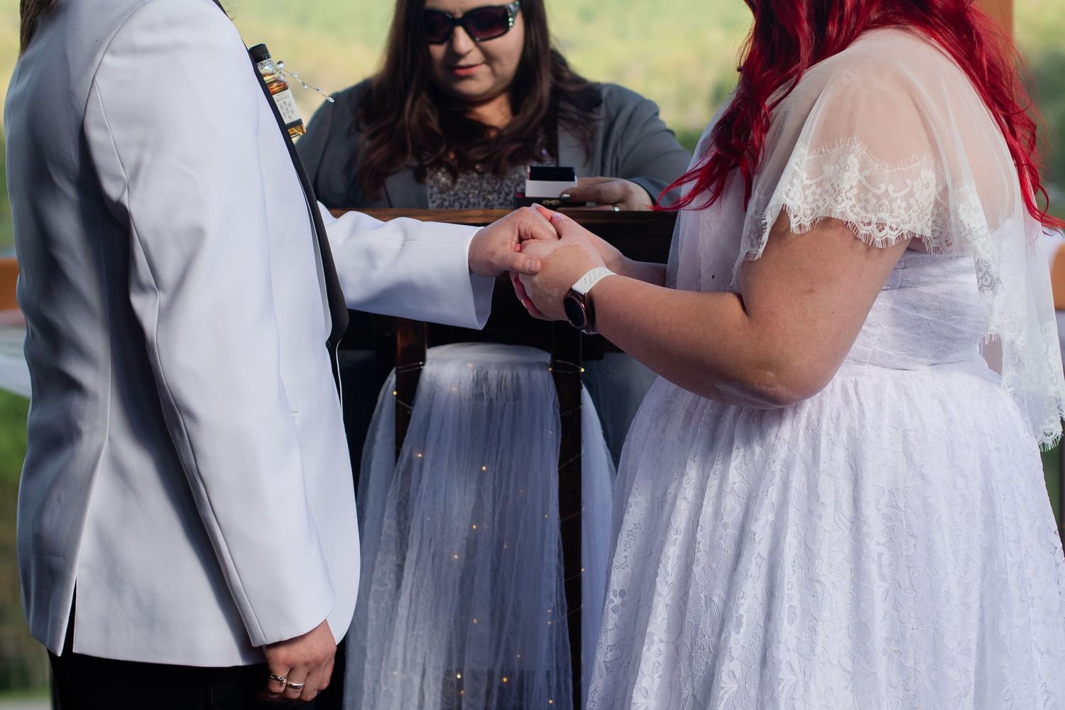 Wedding party members interact on a wooden deck with scenic mountain views.
