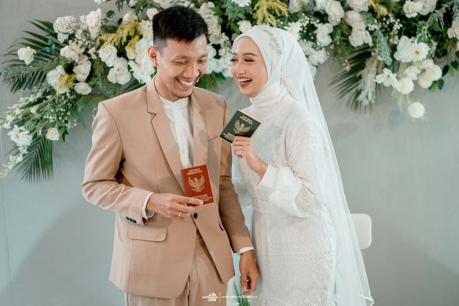 Newlyweds hold official documents during wedding ceremony with floral arrangements.