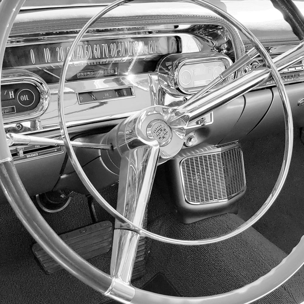 Vintage car dashboard and steering wheel shown in classic black and white photography.