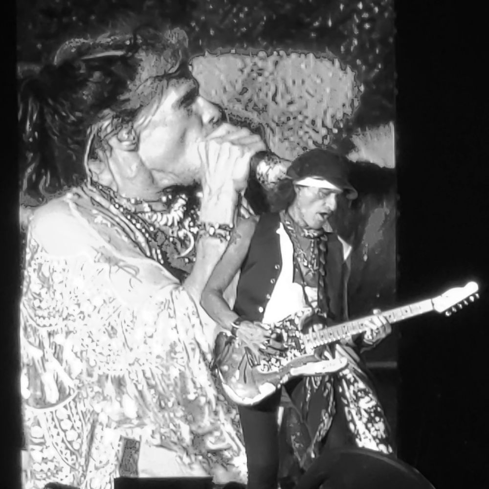 Vintage black and white photo of rock musicians performing on stage with guitars.