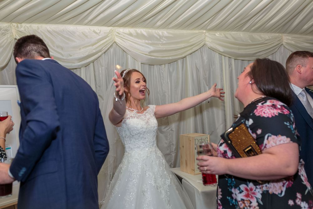 bride arms open wide greets their wedding guest as the enter the marquee for the wedding breakfast