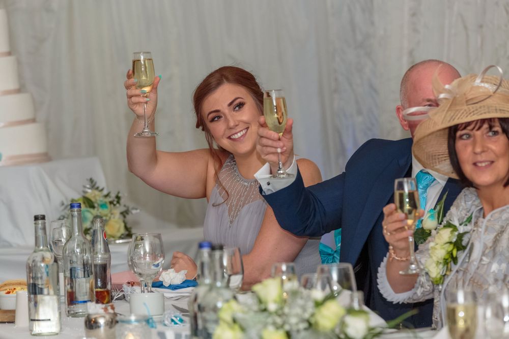 bridesmaid raises a glass in a toast with the mother and father of the groom