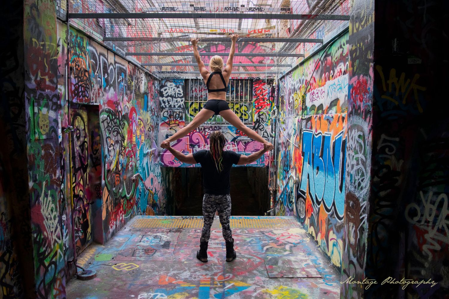 Artistic dance pose captured in graffiti-covered urban tunnel with dramatic lighting.
