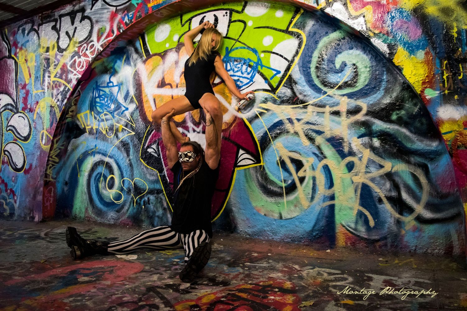 Dancer strikes dynamic pose against vibrant graffiti wall with swirling blue and white patterns.