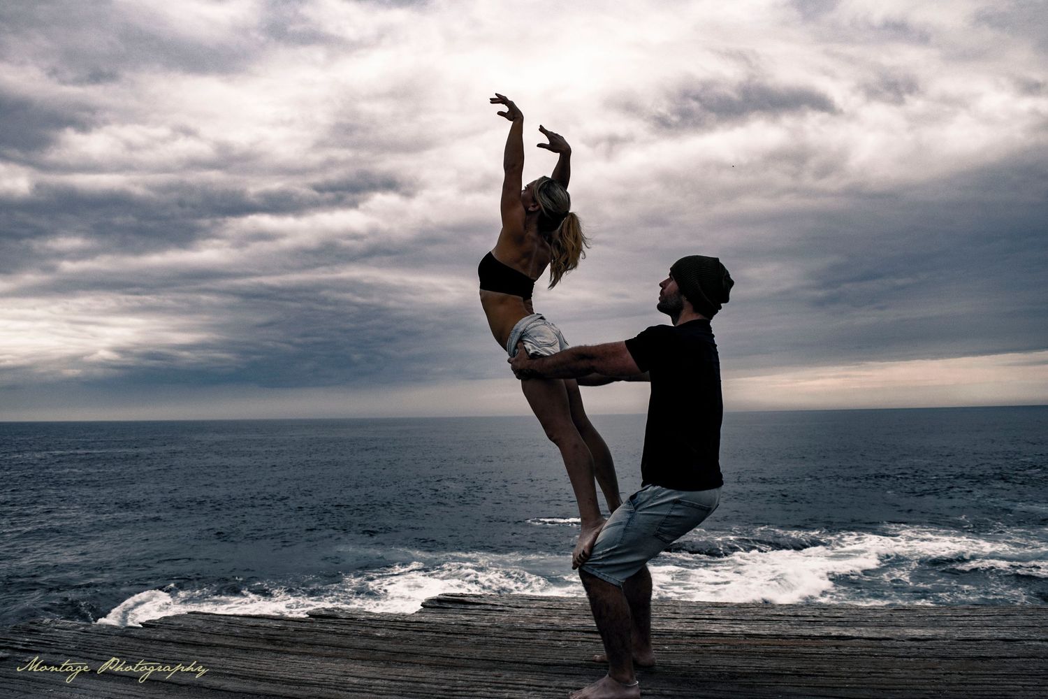 Dramatic dance lift silhouetted against cloudy ocean horizon.