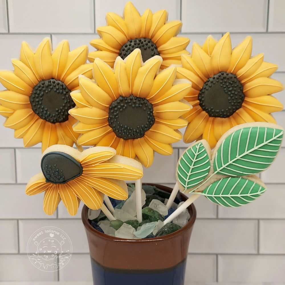 Yellow sunflower cookies on popsicle sticks place in a vase.