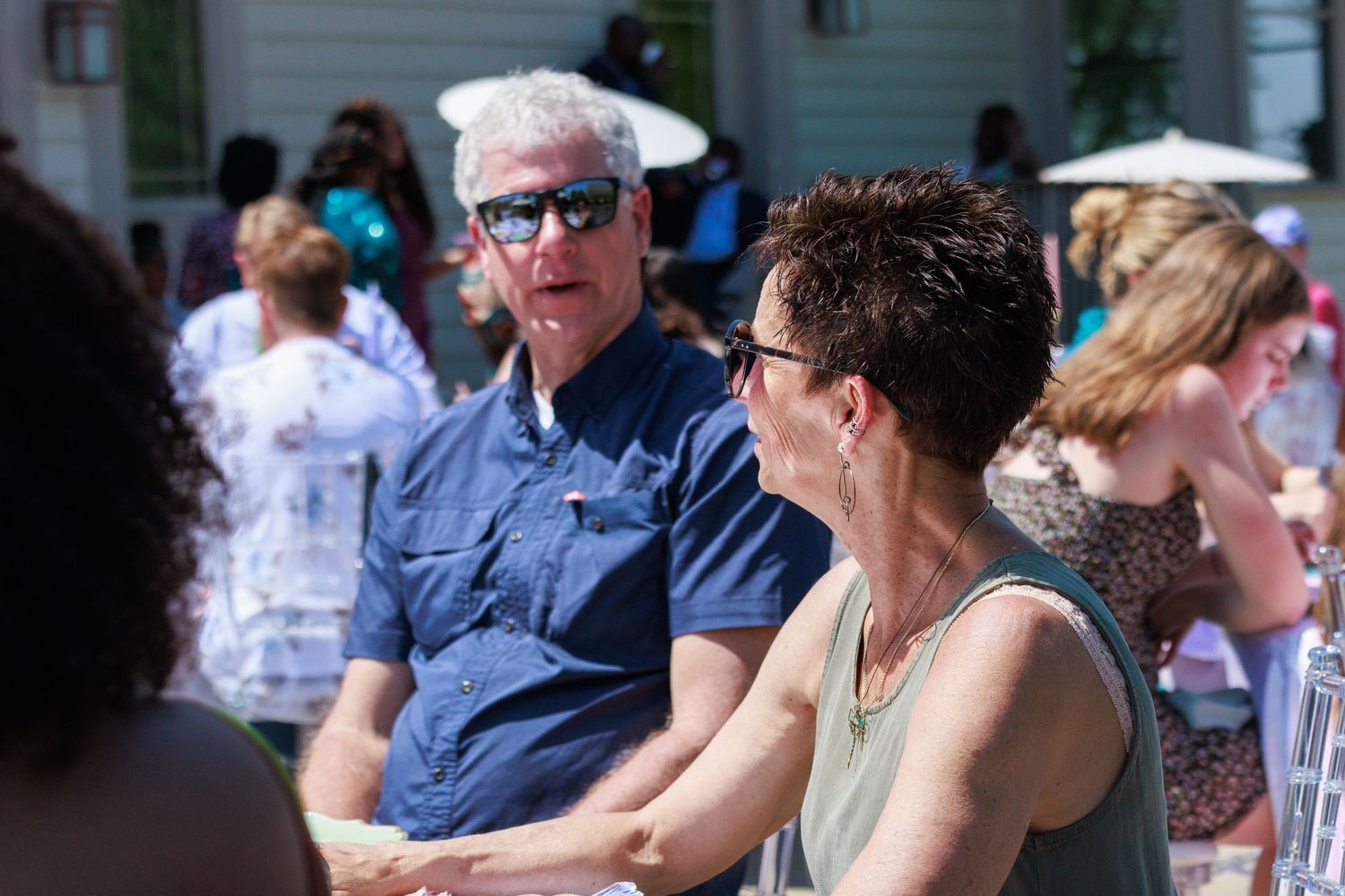 People seated at an outdoor gathering wearing casual summer attire.