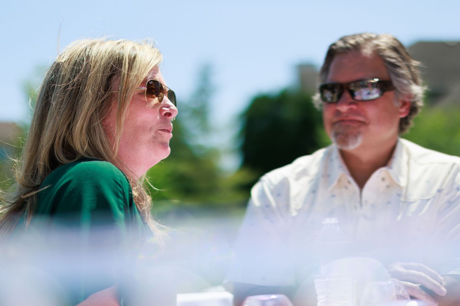 Two people in sunglasses chatting at an outdoor summer gathering.