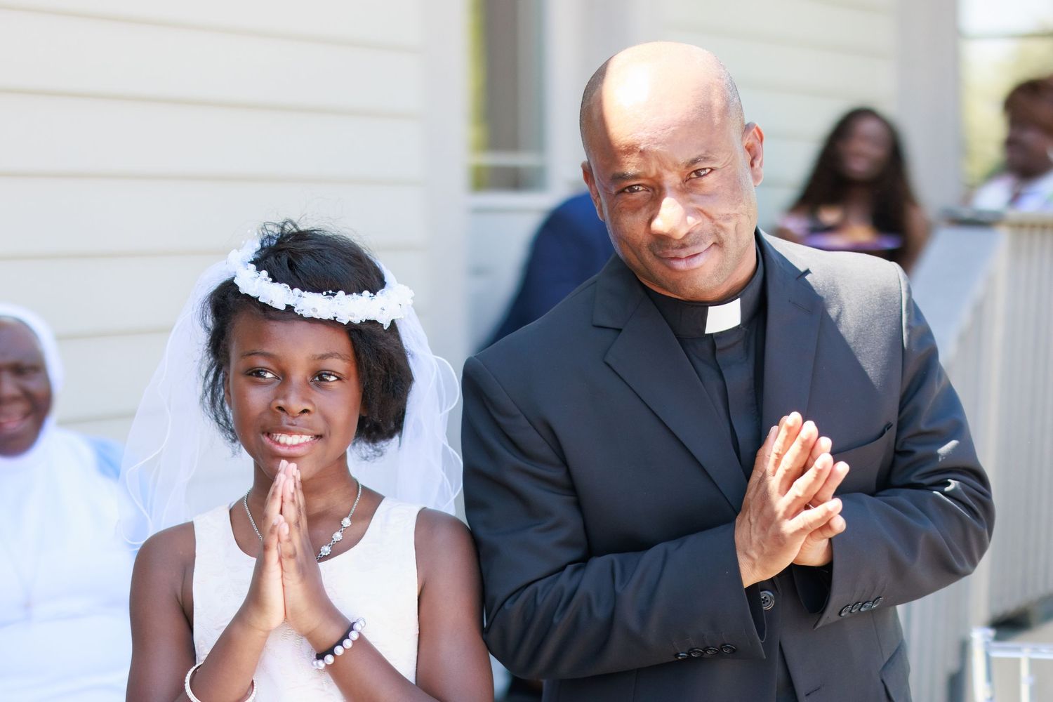 A heartwarming moment between clergy and a young girl in formal attire.