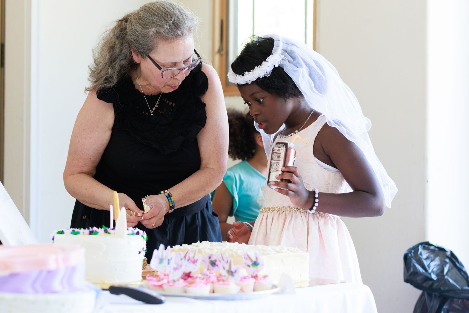 A cake decorating moment shared between two people at a celebration.
