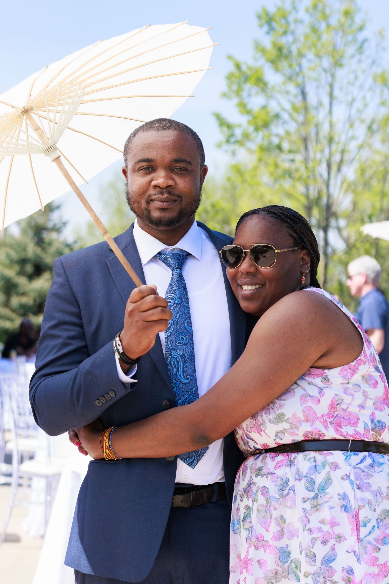 Couple in formal wear sharing romantic moment under white parasol at outdoor event.