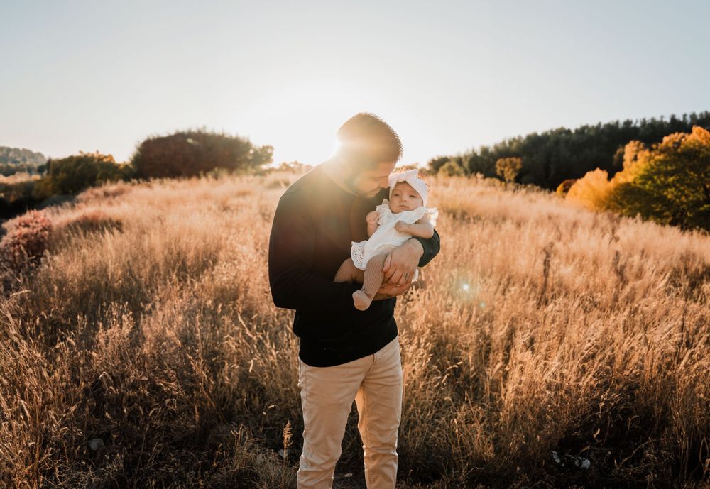 Candid family interaction photographed in a serene outdoor setting during sunset.