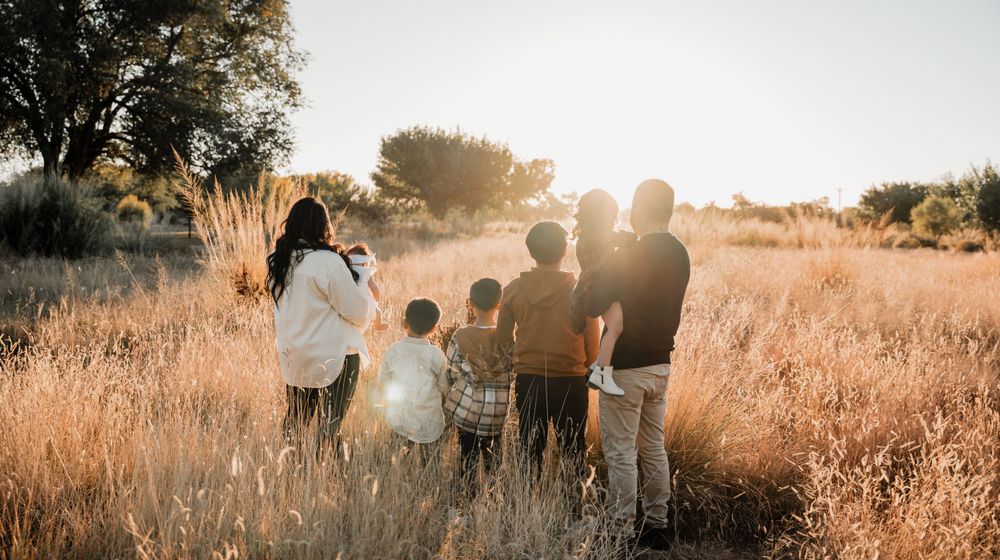 Scenic panoramic view of family bonding time in nature with dramatic sunset lighting.