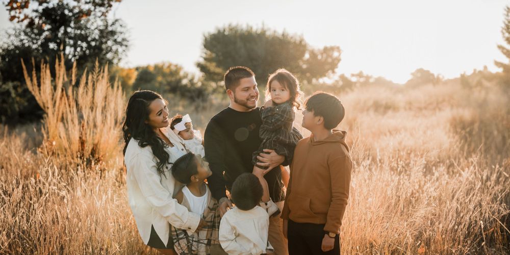 Wide panoramic shot of family togetherness in a golden field during magic hour.