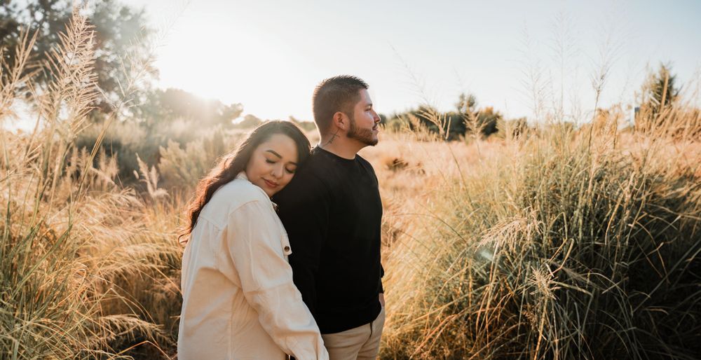 Candid family portrait with warm sunlight streaming through tall grass in an outdoor setting.