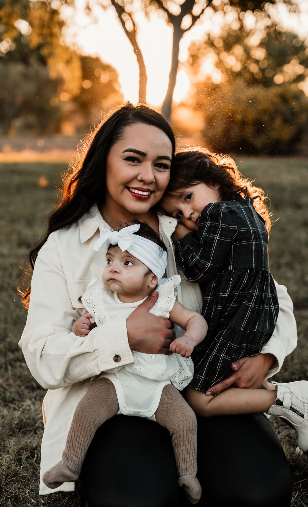 Sweet family moment captured at golden hour with parent and child laughing together in warm sunlit field.