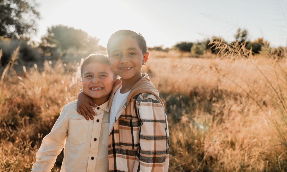 Family members sharing joyful moments together in an autumn field at sunset.