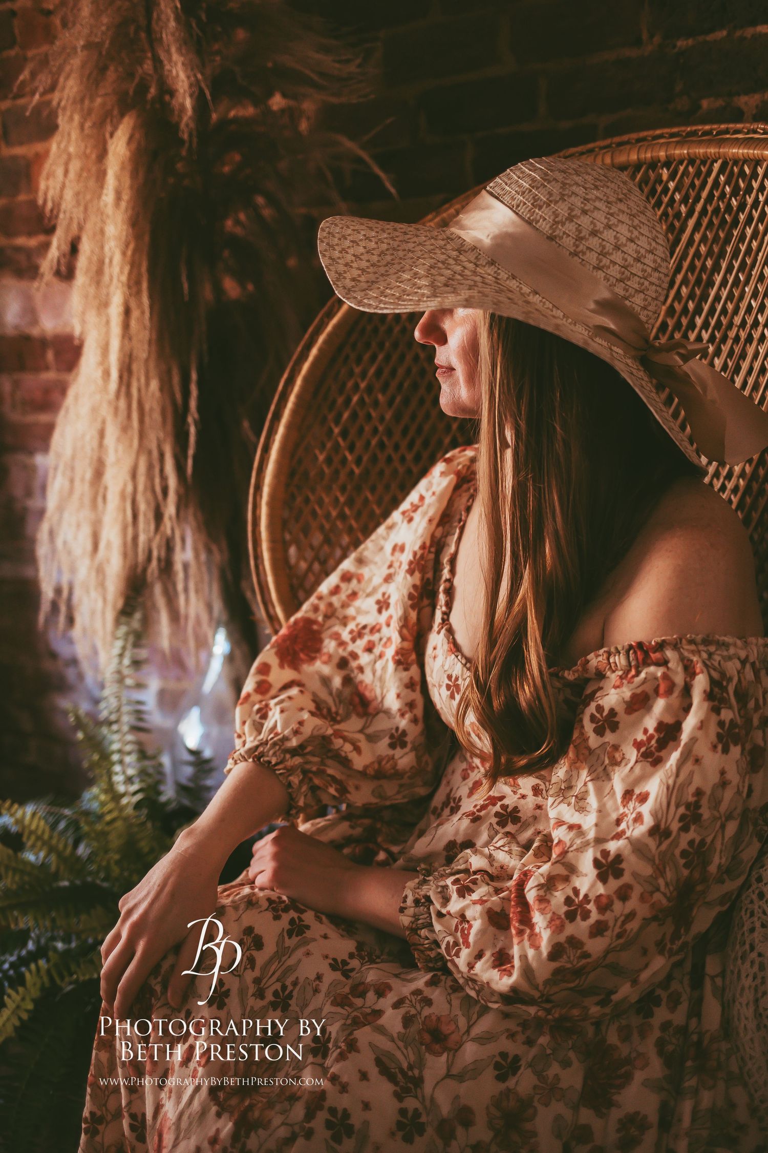 A vintage-inspired portrait featuring a sunhat and floral dress against rustic decor.