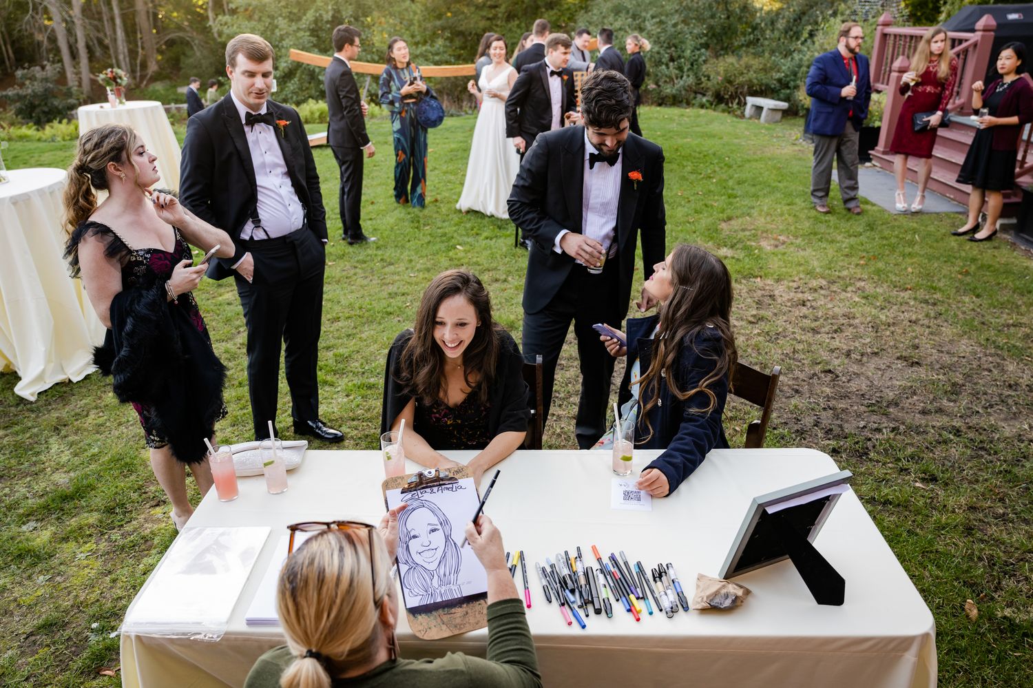 Wedding guests signing a guestbook at an outdoor reception area.