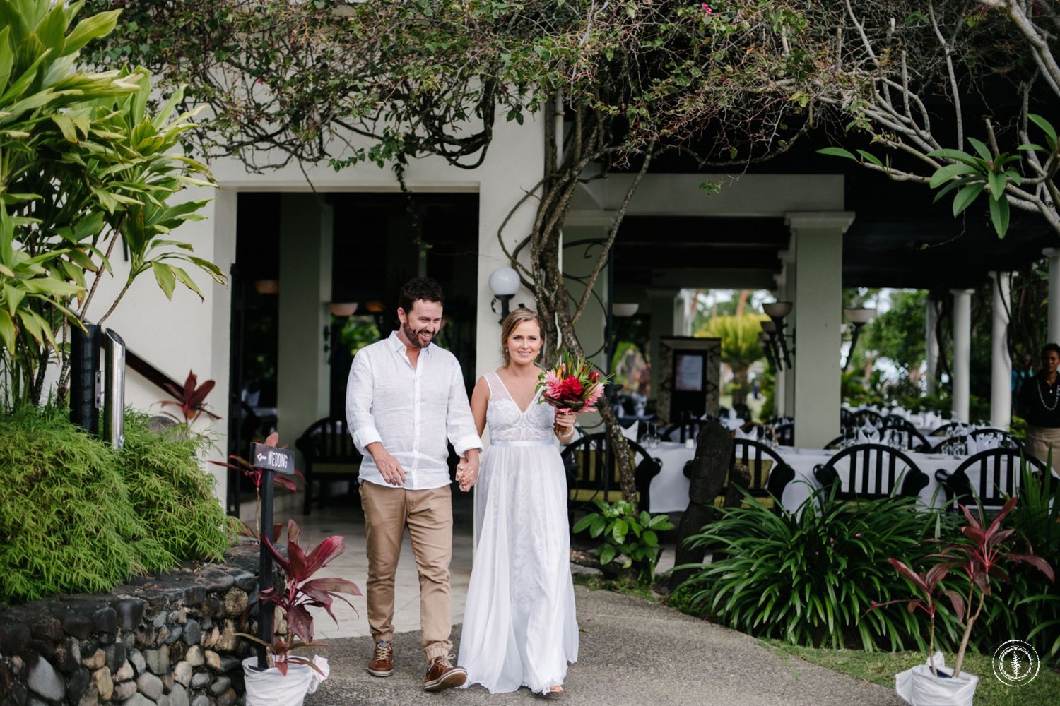 Couple walking through a garden pathway with tropical landscaping.